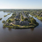 Een villa aan het water in De Wilgen gefotografeerd vanuit de lucht, veel water, veel groen